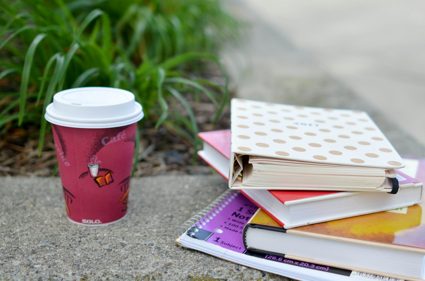 Red coffee cup and colorful notebooks on concrete.